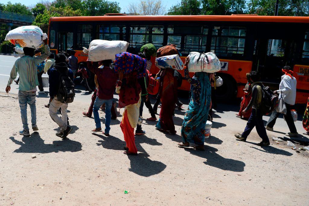 Migrant workers and their family members walk to catch a bus as they leave India's capital for their homes during a government-imposed nationwide lockdown as a preventive measure against the CCP virus in New Delhi, India, on March 29, 2020. (Sajjad Hussain/AFP via Getty Images)