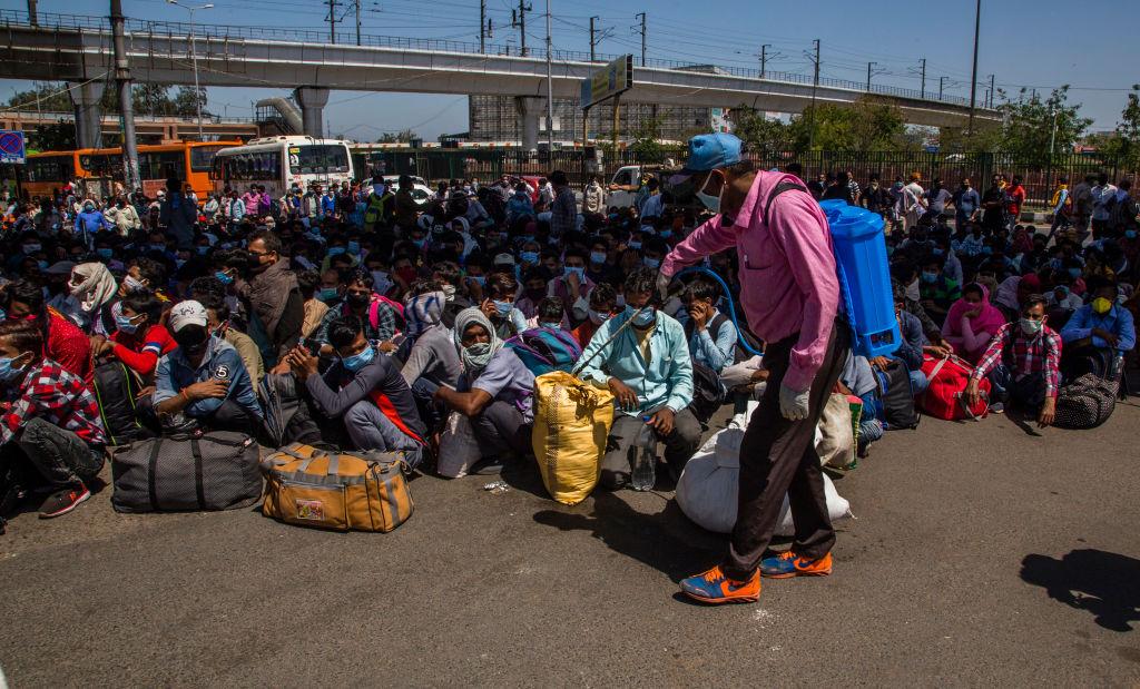 An Indian health worker sprays disinfectant on the luggage of migrant workers and laborers along with their families stuck in the national capital, as they wait to board buses to return to their native villages in Ghaziabad, on the outskirts New Delhi, at border with Uttar Pradesh state on March 29, 2020. (Yawar Nazir/Getty Images)