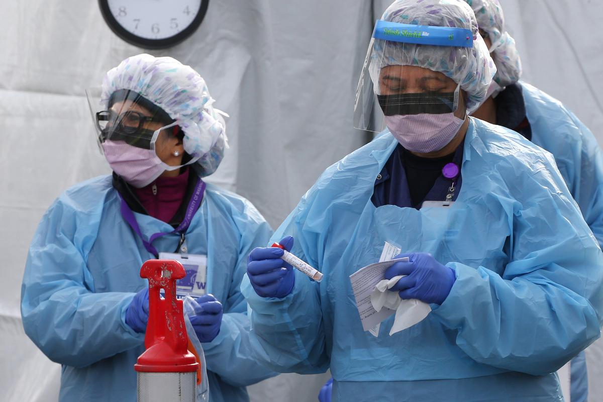 Nurses process a sample for COVID-19 at a drive-up clinic set up by the University of Washington Medical Center's Northwest Outpatient Medical Center in Seattle, Washington, on March 17, 2020 (©Getty Images | <a href="https://www.gettyimages.com/detail/news-photo/nurses-process-a-sample-for-covid-19-after-a-patient-was-news-photo/1207534293?adppopup=true">Karen Ducey</a>)