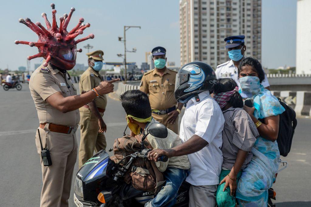 Police inspector Rajesh Babu wearing a CCP virus-themed helmet speaks to a family on a motorbike at a checkpoint in Chennai. (ARUN SANKAR/AFP via Getty Images)