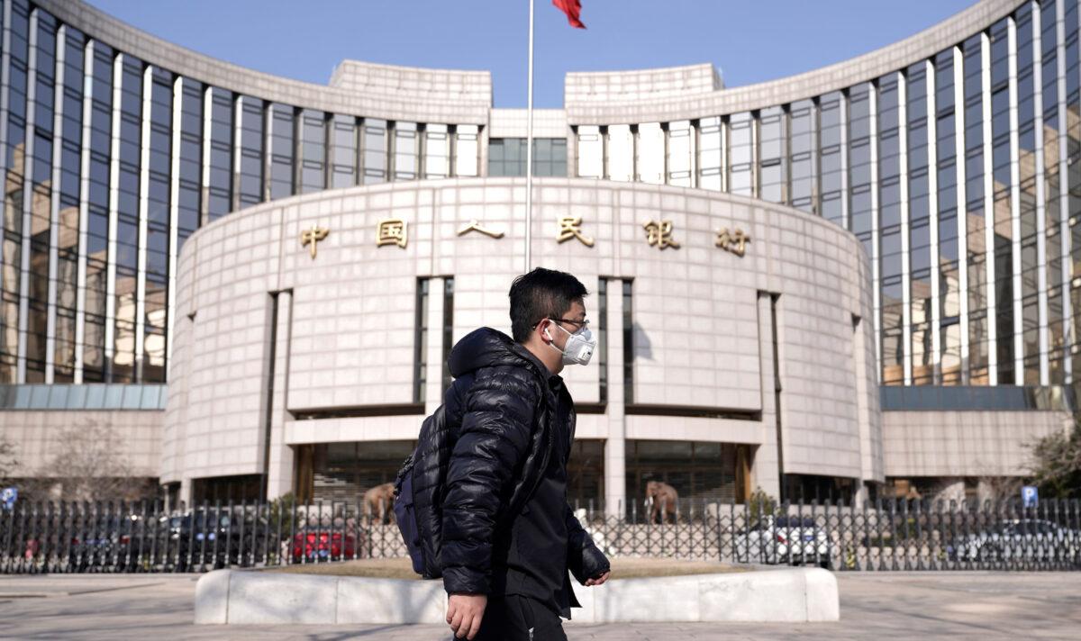 A man wearing a mask walks past the headquarters of the People's Bank of China, the central bank, in Beijing, China, on Feb. 3, 2020. (Jason Lee/Reuters)