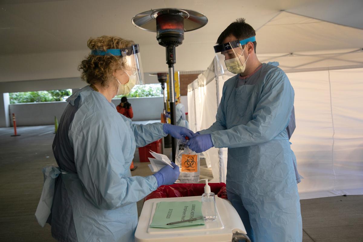 Nurses handle a potentially infected swab at a drive-through testing center at the University of Washington Medical Campus in Seattle. (©Getty Images | <a href="https://www.gettyimages.com/detail/news-photo/nurses-wearing-protective-clothing-handle-a-bag-with-a-news-photo/1212276863?adppopup=true">John Moore</a>)