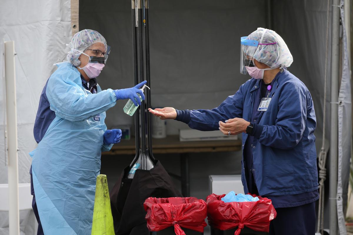 Nurses disinfect their hands at a drive-up clinic at the University of Washington Medical Center's Northwest Outpatient Medical Center on March 17, 2020. (©Getty Images | <a href="https://www.gettyimages.com/detail/news-photo/nurses-clean-their-hands-with-disinfectant-after-a-patient-news-photo/1207534457?adppopup=true">Karen Ducey</a>)
