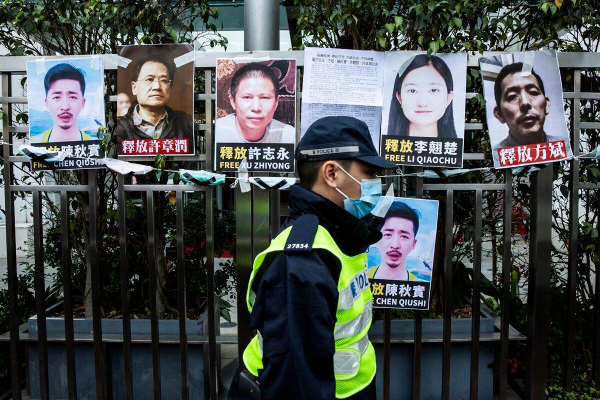 A police officer walks past placards of detained rights activists taped on the fence of the Chinese liaison office, in protest against Beijing's detention of prominent anti-corruption activist Xu Zhiyong, in Hong Kong, China, on Feb. 19, 2020.  (Isaac Lawrence/AFP via Getty Images)