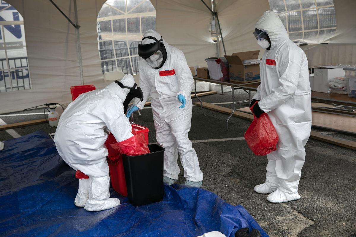 Nurses dressed in personal protective equipment (PPE) dispose of medical waste at a drive-thru coronavirus testing station in Stamford, Connecticut, on March 23, 2020. (John Moore/Getty Images)