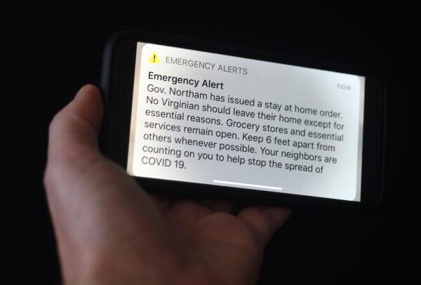 An emergency alert message from the state of Virginia to issue a "stay at home" order is displayed on a smartphone in Arlington, Virginia, on March 30, 2020. (Olivier Douliery/AFP via Getty Images)