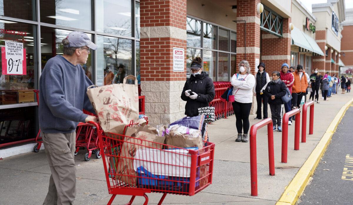 A shopper passes a self-distancing queue outside Trader Joe's, as the company limited the number of shoppers allowed in the store to help prevent the spread the CCP virus, in Bailey's Crossroads, Virginia, on March 31, 2020. (Kevin Lamarque/File Photo/Reuters)