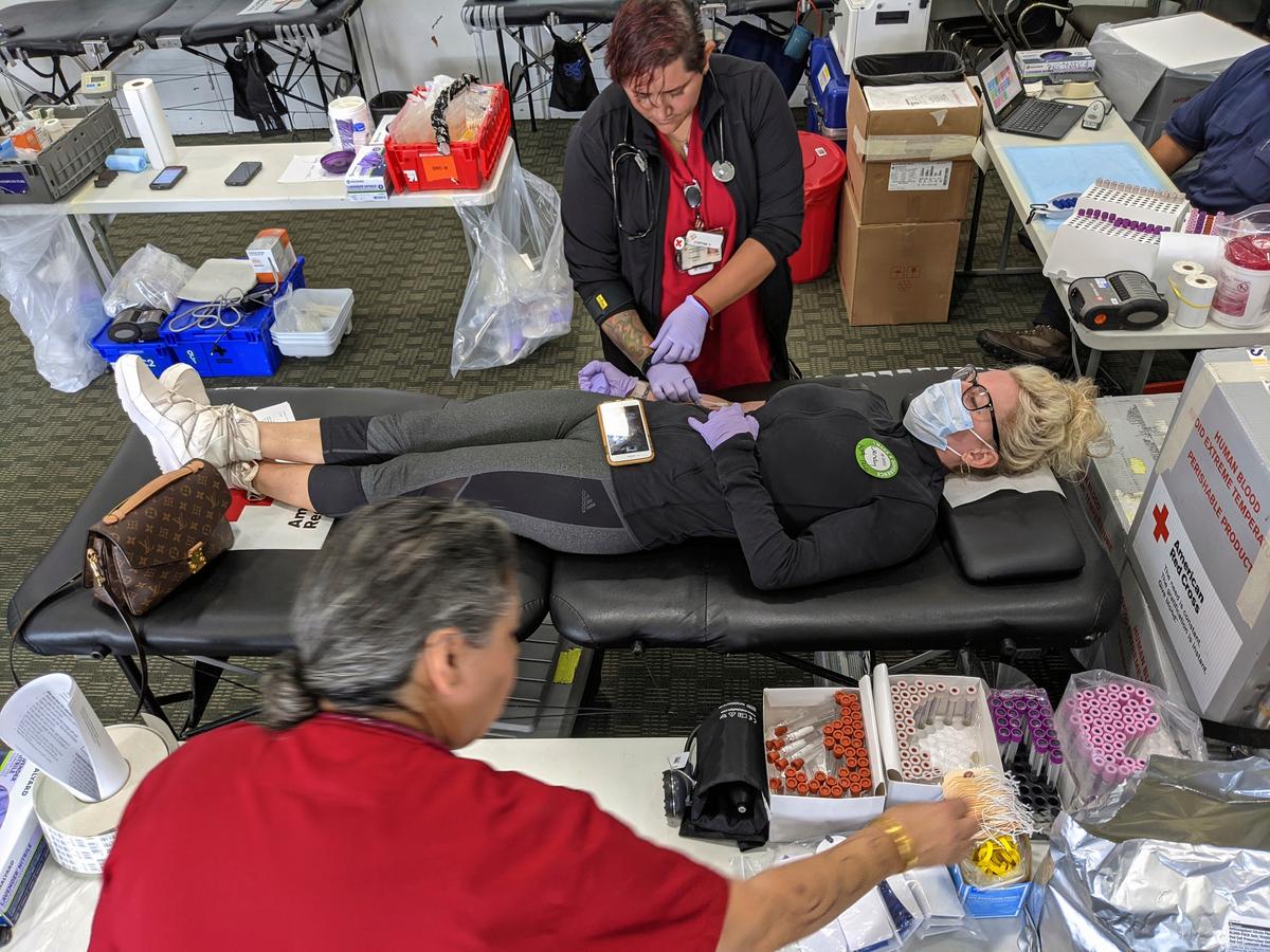 Phlebotomist Cynthia Viteri, top, monitors donor Wendy Tuttle, a hospitality industry recruiter from Mar Vista, Calif., wearing a protective mask and gloves, as she donates blood for the first time at the American Red Cross office in Santa Monica, Calif., on March 26, 2020. (Damian Dovarganes/AP Photo)