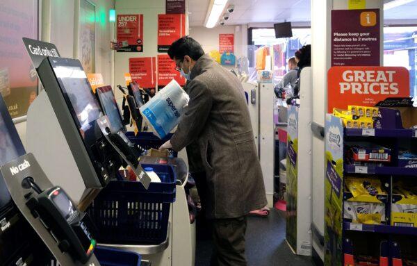 A shopper, wearing a mask as a precautionary measure against COVID-19, scans a pack of toilet rolls through a self-scan checkout till, inside a Sainsbury's supermarket store in north London on March 31, 2020. (Isabel Infantes/AFP via Getty Images)
