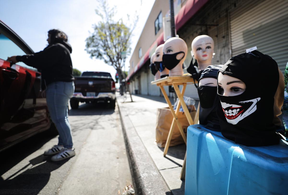 A street vendor sells protective masks to a customer amid the CCP virus pandemic in Los Angeles, California, on March 30, 2020. (Mario Tama/Getty Images)