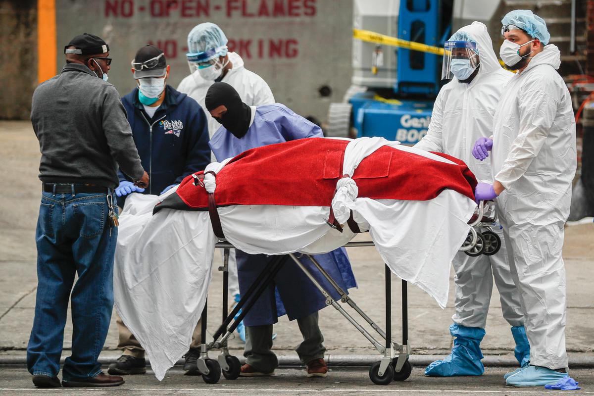 A body wrapped in plastic that was unloaded from a refrigerated truck is handled by medical workers wearing personal protective equipment due to COVID-19 concerns at Brooklyn Hospital Center in New York City on March 31, 2020. (John Minchillo/AP Photo)