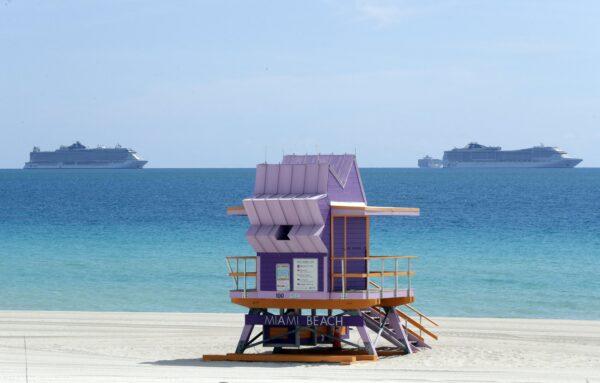 Two cruise ships are anchored offshore past a lifeguard tower, on March 31, 2020, in Miami Beach, Fla. (Wilfredo Lee/AP Photo)