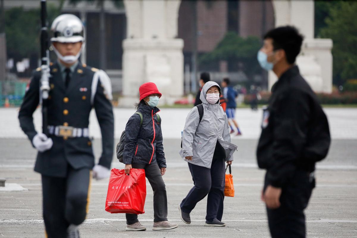 Tourists wear protective face masks to protect themselves from coronavirus disease (COVID-19) while passing by a flag rising ceremony at Chiang Kai Shek Memorial Hall in Taipei, Taiwan, on March 11, 2020. (Ann Wang/Reuters)