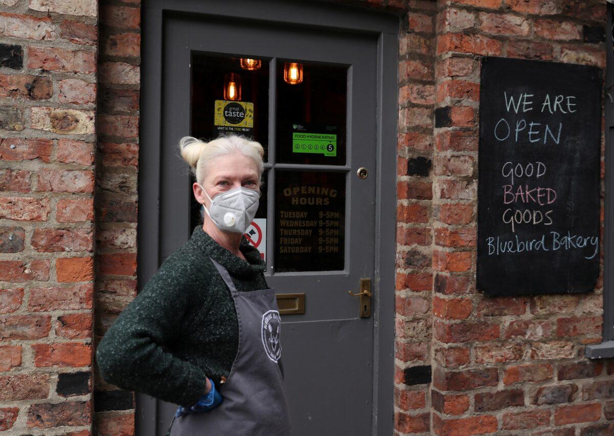 A woman wearing a protective mask stands outside a bakery in York as the spread of the CCP virus outbreak, in York, Britain on March 31, 2020. (Lee Smith/Reuters)