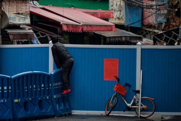 A resident peers over a barrier set up to prevent people from entering in Wuhan, in China's central Hubei province, on Feb. 29, 2020. (STR/AFP via Getty Images)