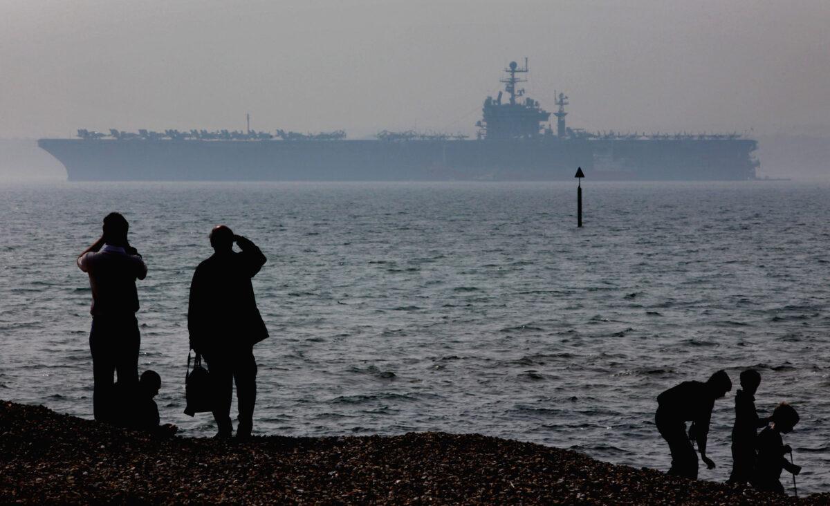 People stop to look at the USS Theodore Roosevelt anchored off Stokes Bay in Portsmouth, England, on April 6, 2009. (Matt Cardy/Getty Images)