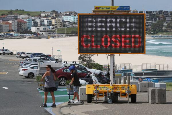 People walk past a "Beach Closed" sign at Bondi Beach, during the COVID-19 outbreak, in Sydney, Australia, on April 1, 2020. (Reuters/Loren Elliott)