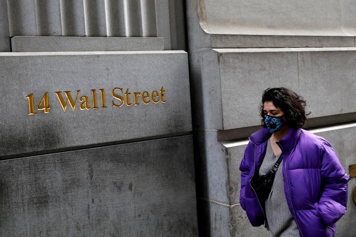 A woman wearing a protective mask walks along Wall Street after further cases of COVID-19 were confirmed in New York City, New York, on March 6, 2020. (Reuters/Andrew Kelly)