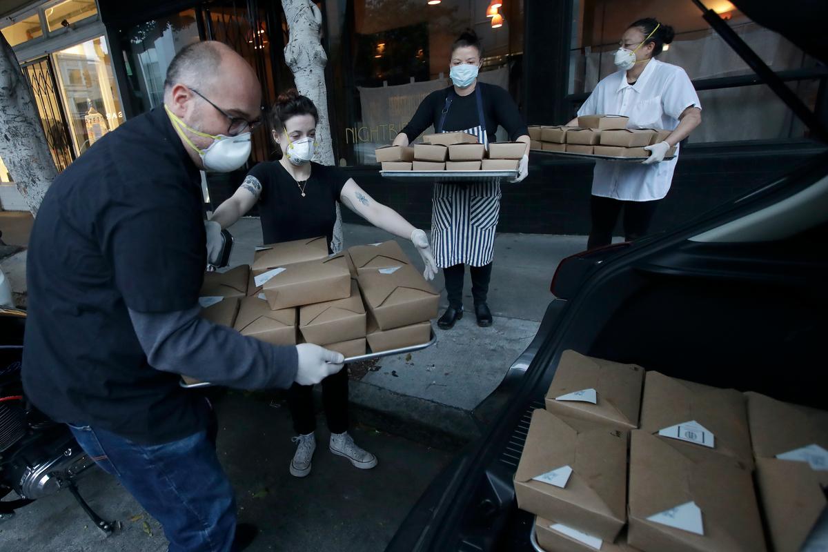 Nightbird Restaurant staff pack dinner boxes into Kim Alter's car. (AP Photo/Jeff Chiu)