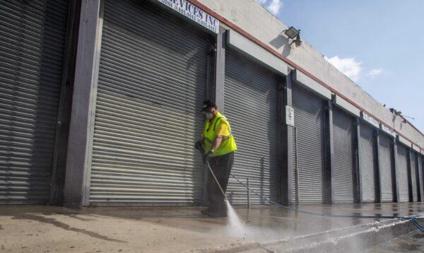 A member of the LA Fashion District Clean Team disinfects a side walk in the Fashion District in Downtown Los Angeles, Calif., on April 2, 2020. (Apu Gomes/AFP via Getty Images)