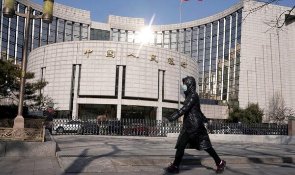 A woman walks past the headquarters of China's central bank in Beijing, on Feb. 3, 2020. (Jason Lee/Reuters)
