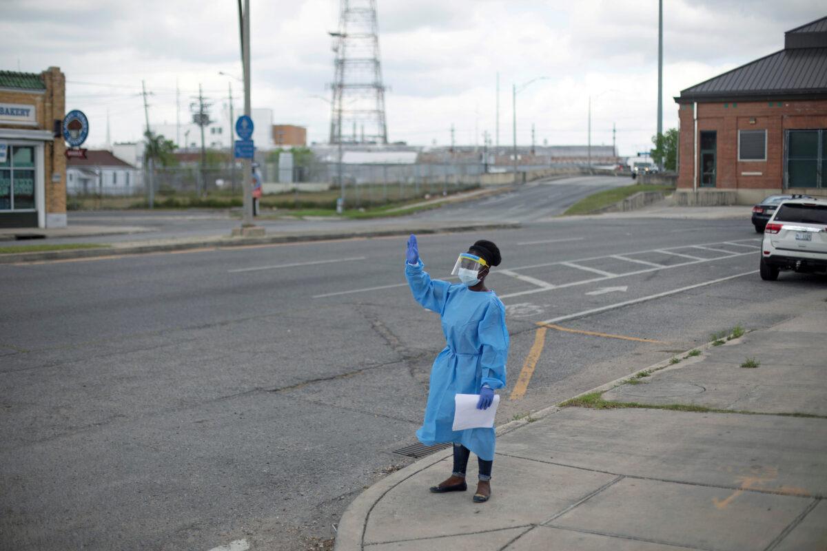 A staff member of Odyssey House Louisiana, which runs a drive-thru testing site for the CCP virus, waves to passing vehicles in New Orleans, Louisiana, on March 27, 2020. (Kathleen Flynn/Reuters)