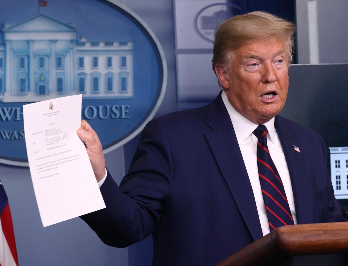 President Donald Trump holds up the results of his CCP virus test in the press briefing room with members of the White House Coronavirus Task Force in Washington on April 2, 2020. (Win McNamee/Getty Images)