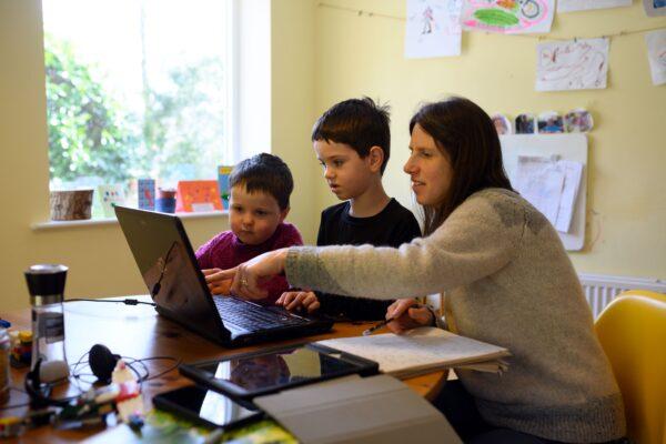 Children are assisted by their mother as they navigate online learning resources during the CCP virus lockdown in Huddersfield, England, on March 23, 2020. (Oli Scarff/AFP via Getty Images)