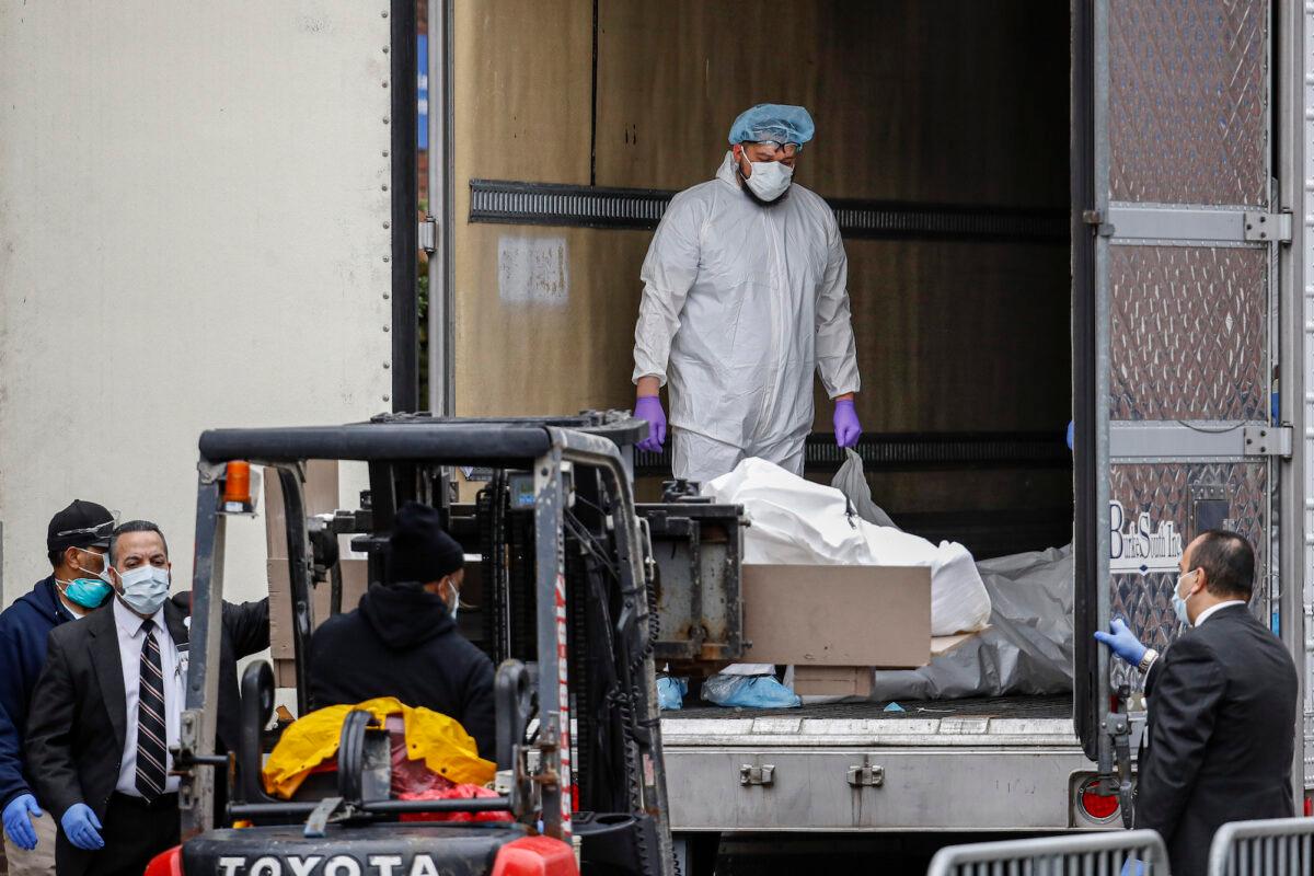 A medical worker in protective gear stands in a refrigerated container truck used as a temporary morgue at Brooklyn Hospital Center in New York City on March 31, 2020. (John Minchillo/AP Photo)