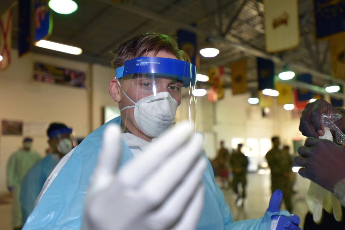 An army specialist inspects his glove fit while awaiting to forward deploy to a CCP virus testing site in Plymouth Meeting, Pennsylvania, on April 2, 2020. (Pennsylvania National Guard/Master Sgt. George Roach/Handout via Reuters)