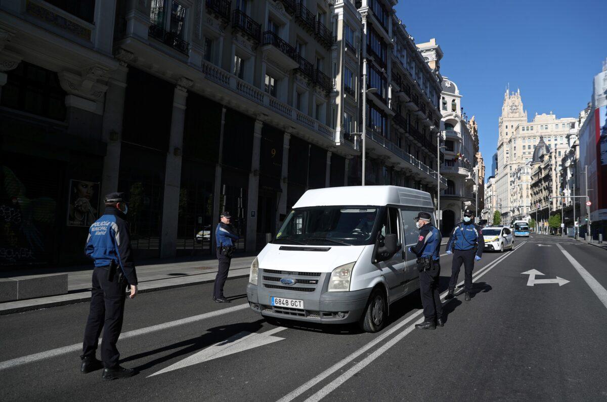 Municipal police officers wearing masks check a car during the CCP virus outbreak in Madrid on April 4, 2020. (Susana Vera/Reuters)