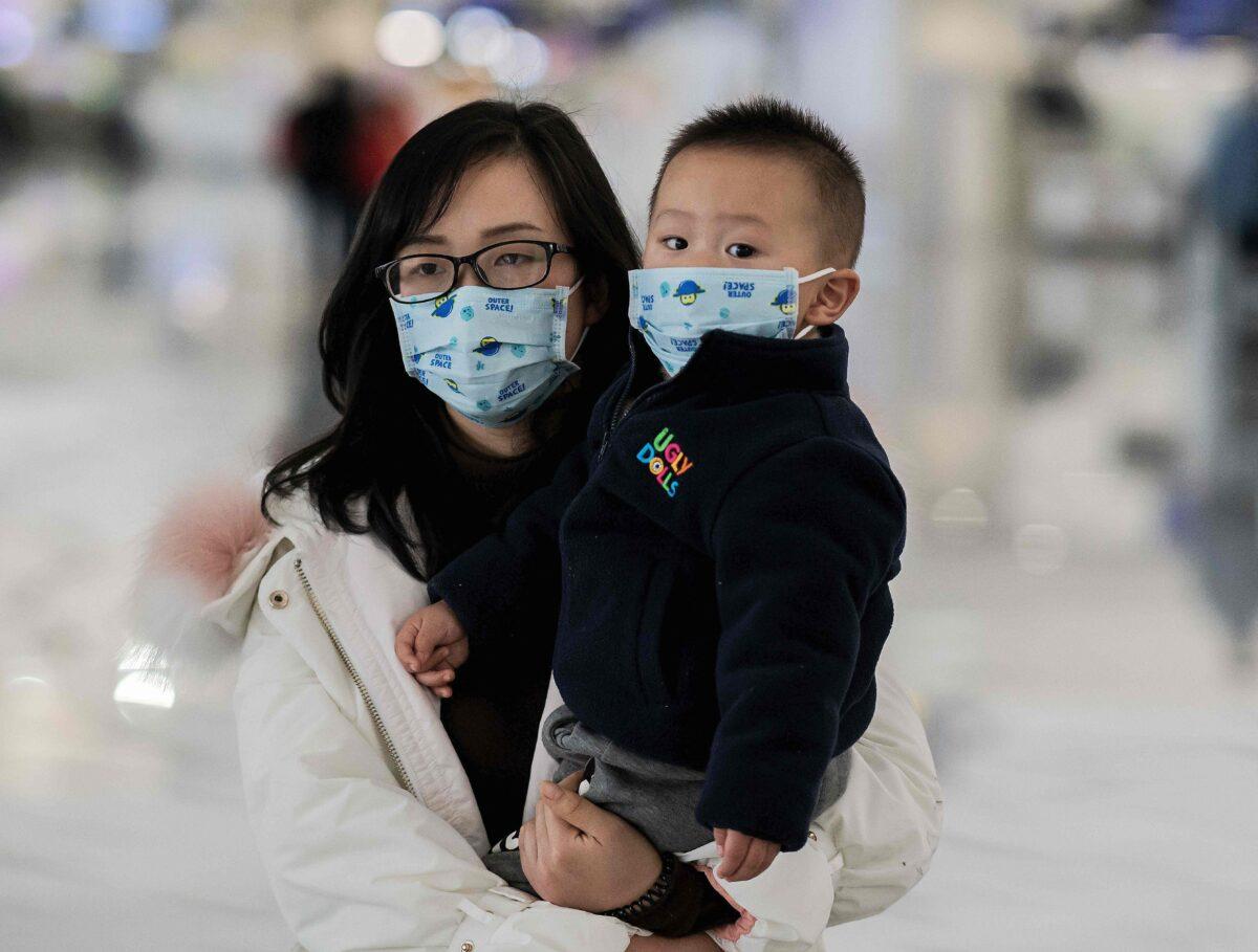 A woman and a child wearing protective masks walk toward check-in counters at Daxing international airport in Beijing on Jan. 21, 2020. (Nicolas Asfouri/AFP via Getty Images)