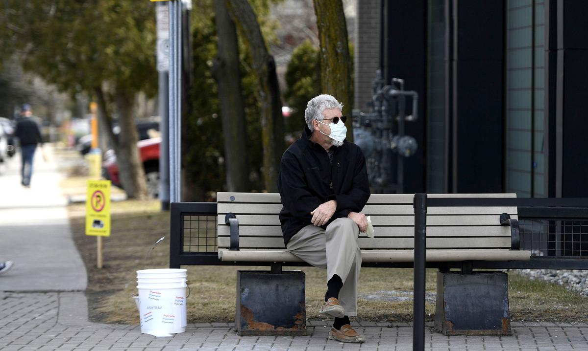 A man wears a mask for protection against COVID-19 while waiting outside a store in Ottawa, Canada, on April 4, 2020. (Justin Tang/The Canadian Press)