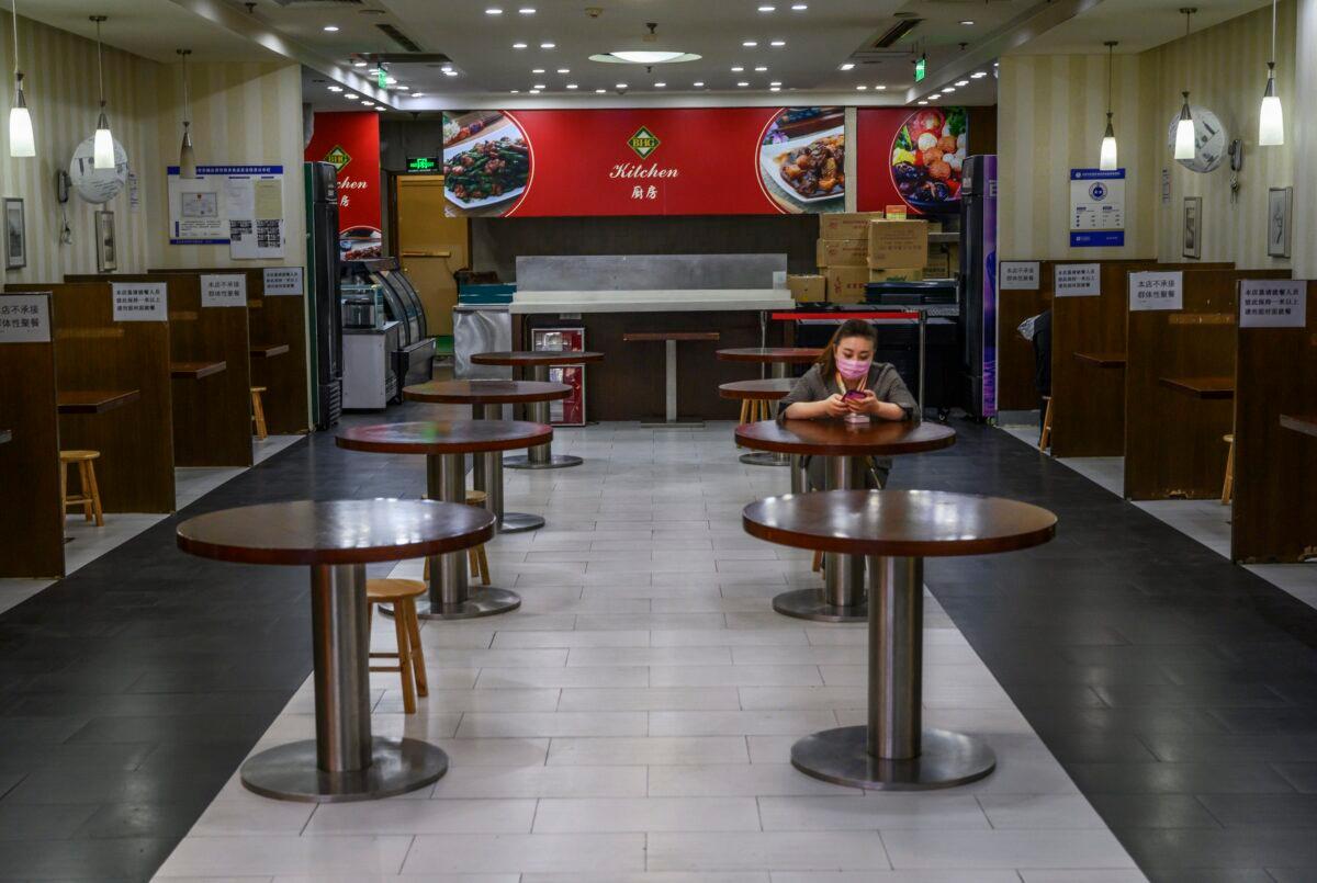A Chinese woman waits for customers in a nearly empty restaurant at a shopping mall in Beijing, China, on March 26, 2020. (Kevin Frayer/Getty Images)
