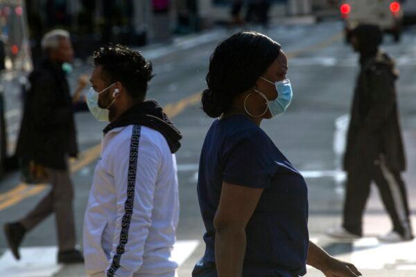 People wear masks as they walk along 34th street in New York City on April 6, 2020. (Kena Betancur/Getty Images)