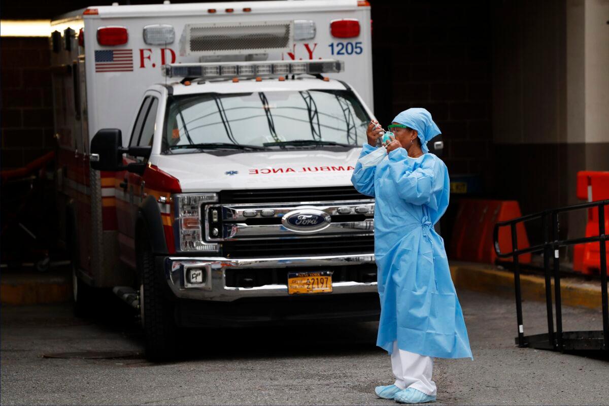 An emergency room nurse dons her face protectors after taking a break in a driveway for ambulances and emergency medical services vehicles outside Brooklyn Hospital Center's emergency room in New York, during the CCP virus crisis on April 5, 2020. (Kathy Willens/AP Photo)