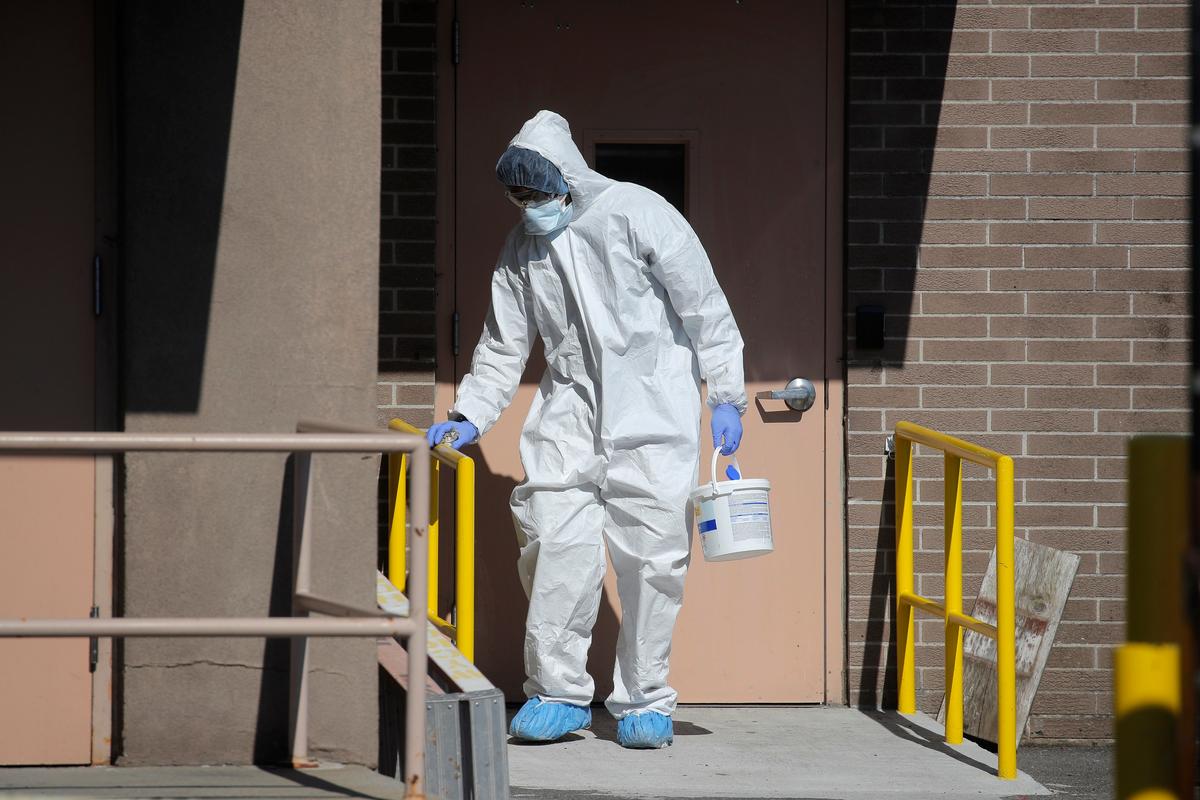A worker disinfects handrails at the emergency entrance outside the Wyckoff Heights Medical Center during the outbreak of the CCP virus in the Brooklyn borough of New York City, New York on April 6, 2020. (Brendan Mcdermid/Reuters)