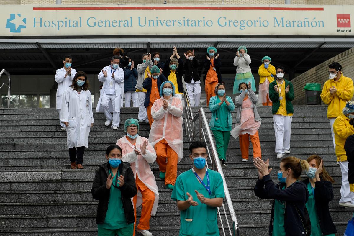 Staff members of the Gregorio Maranon Hospital applaud to pay tribute to cleaning workers in Madrid on April 1, 2020. (OSCAR DEL POZO/AFP via Getty Images)