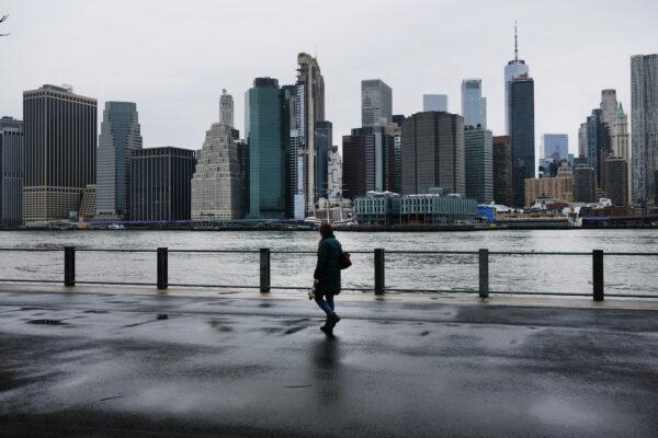 People walk in Brooklyn, with lower Manhattan looming in the background, on March 28, 2020. (Photo by Spencer Platt/Getty Images)