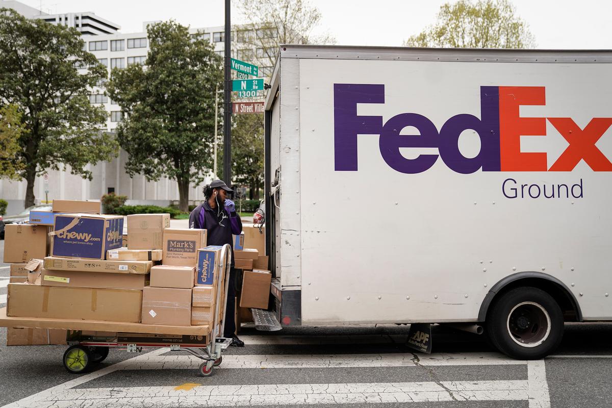 A FedEx worker unloads packages from his delivery truck on March 31, 2020, in Washington. (Drew Angerer/Getty Images)