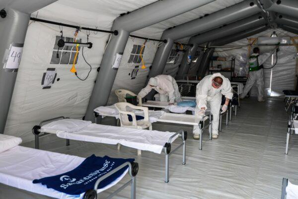 Cleaning personnel in protective gear disinfecting patients' beds in one of the tents from a newly operative field hospital for coronavirus patients, in Cremona, southeast of Milan, on March 20, 2020. (Miguel Medina/AFP/Getty Images)