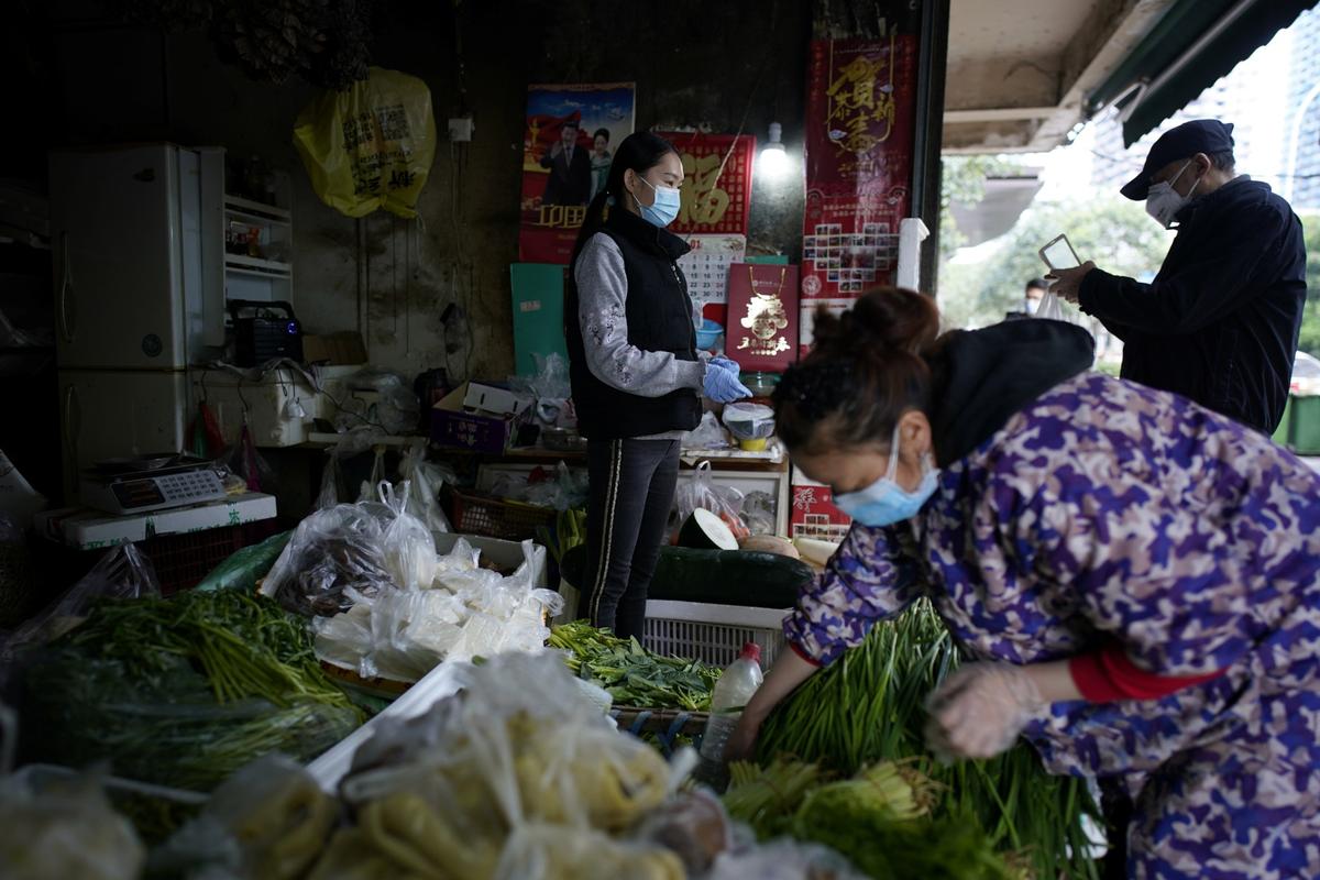 People wearing face masks buy vegetables at a street market in Wuhan, Hubei Province, China, on April 6, 2020. (Aly Song/Reuters)