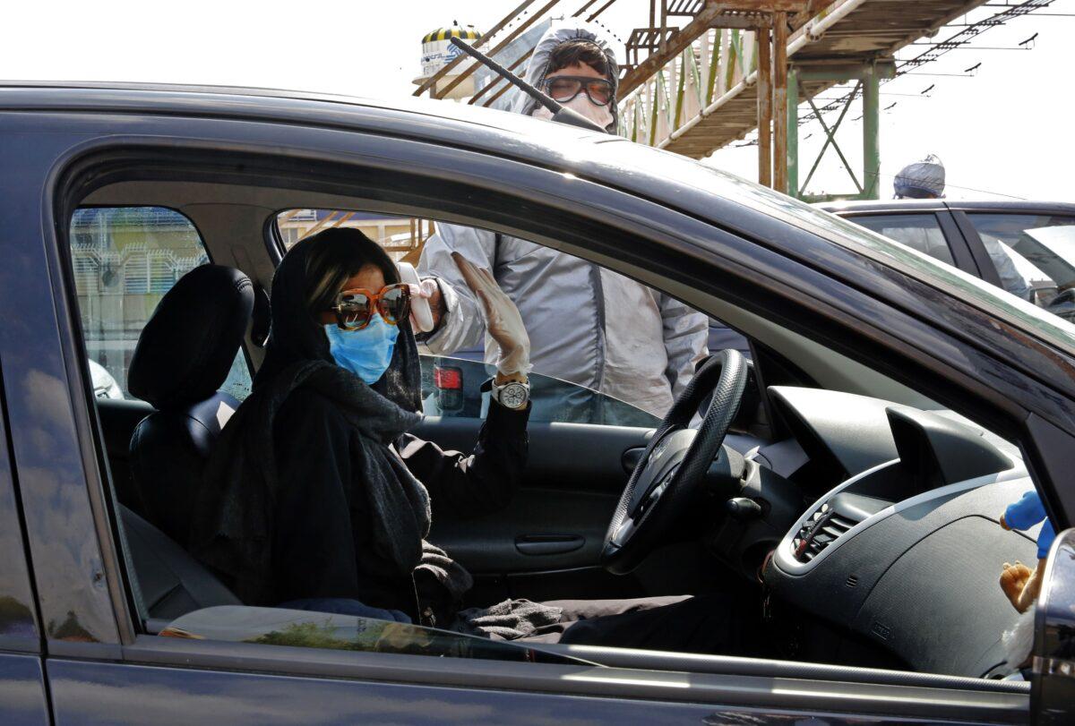 Members of the Iranian Red Crescent test people for COVID-19 symptoms outside Tehran, Iran, on March 26, 2020. (STR/AFP/Getty Images)