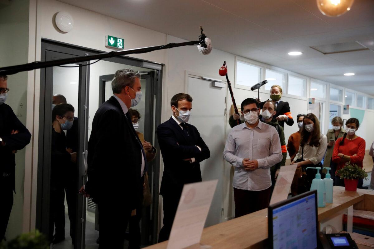 French President Emmanuel Macron, wearing a protective mask, talks with health workers as he visits a medical center in Pantin near Paris on April 7, 2020. (Gonzalo Fuentes/Pool/Reuters)