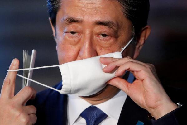 Japan's Prime Minister Shinzo Abe takes off his face mask as he arrives to speak to the media on Japan's response to the coronavirus disease (COVID-19) outbreak, at his official residence in Tokyo, Japan, on April 6, 2020. (Issei Kato/Reuters)