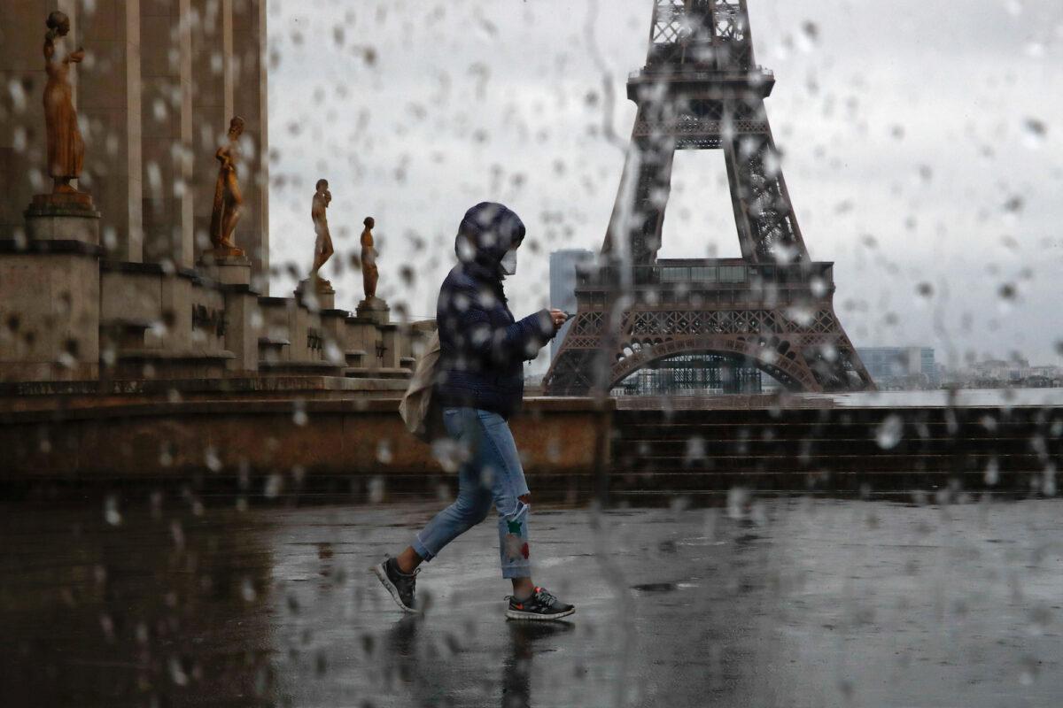 A woman with a protective mask walks past the Eiffel tower in Paris on April 6, 2020. (Gonzalo Fuentes/Reuters)