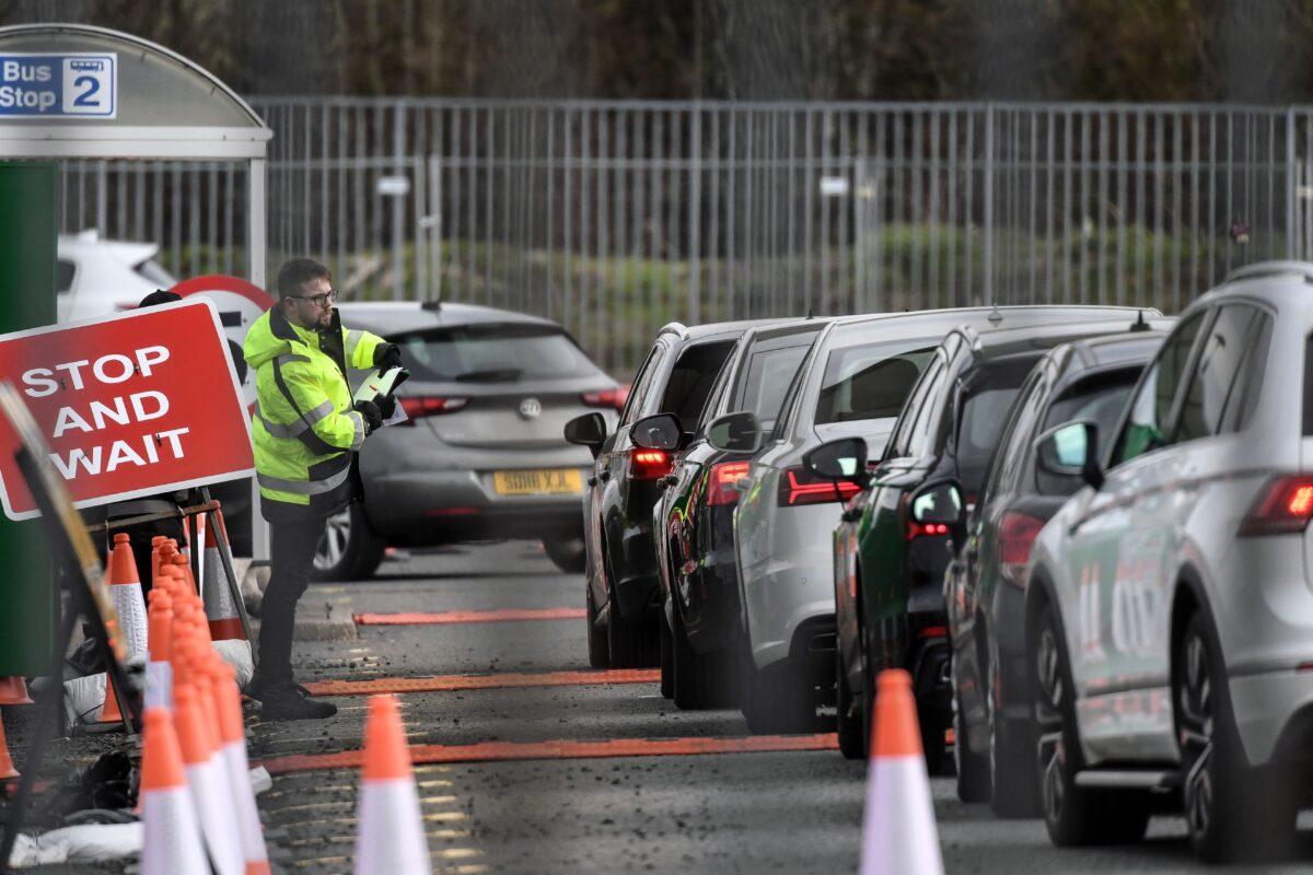 A steward works as cars line up to enter a drive-in facility set up to test NHS staff for the CCP virus at Glasgow Airport in Paisley, Scotland, on April 5, 2020. (Andy Buchanan/AFP via Getty Images)