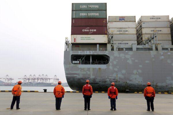 Workers watch a container ship arrive at a port in Qingdao in east China's Shandong province , China, on Feb. 4, 2020. (Chinatopix via AP)