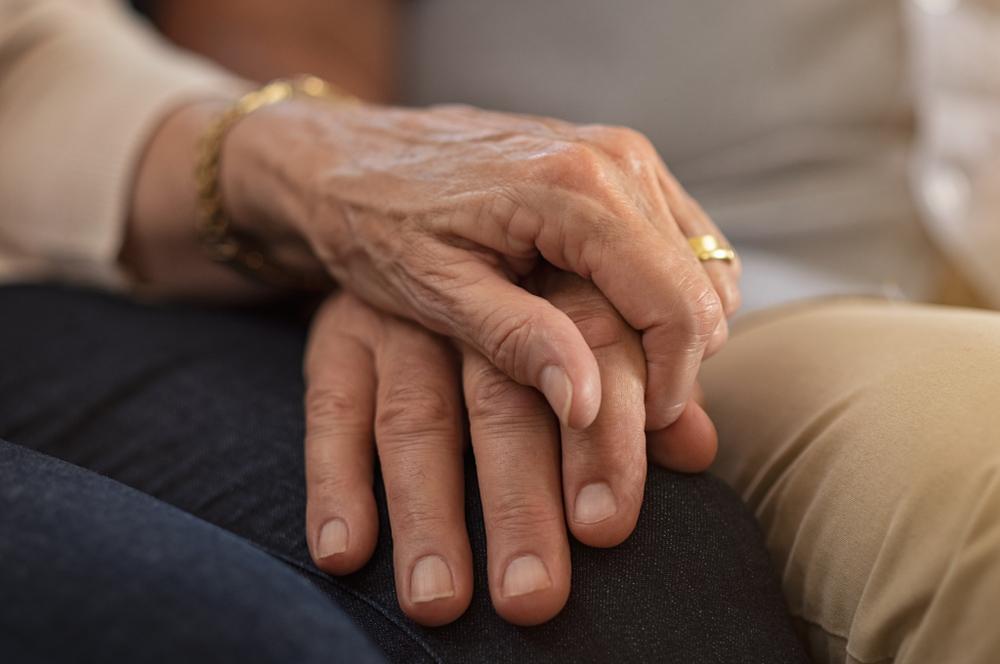 Illustration - Shutterstock | <a href="https://www.shutterstock.com/image-photo/closeup-elderly-couple-holding-hands-while-1221793897">Rido</a>