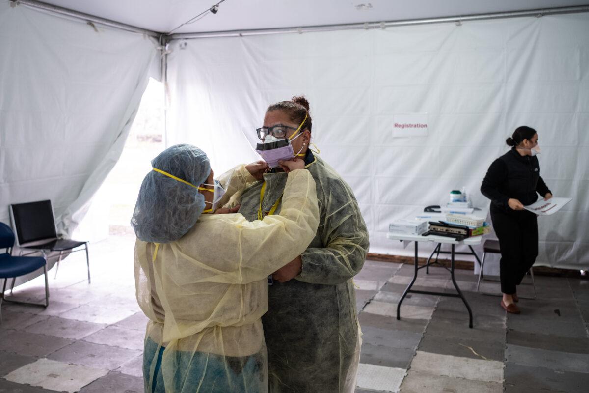 Nurses adjust protective masks inside a testing tent at St. Barnabas hospital on March 20, 2020 in New York City. St. Barnabas hospital in the Bronx set-up tents to triage possible COVID-19 patients outside before they enter the main Emergency department area. (Photo by Misha Friedman/Getty Images)
